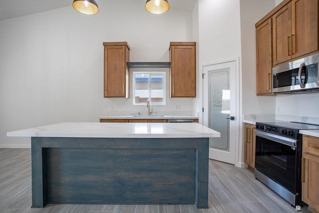 kitchen featuring range with electric stovetop, light wood-style floors, stainless steel microwave, brown cabinets, and a sink