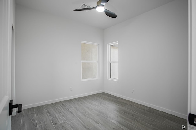 empty room with baseboards, a ceiling fan, dark wood-style flooring, and visible vents