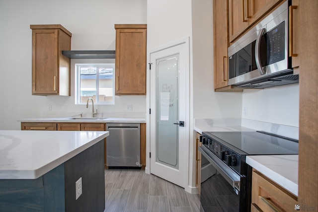kitchen featuring a sink, light countertops, brown cabinetry, stainless steel appliances, and wood tiled floor