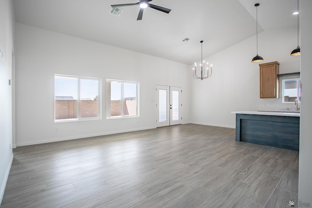 unfurnished living room featuring visible vents, ceiling fan with notable chandelier, and a wealth of natural light
