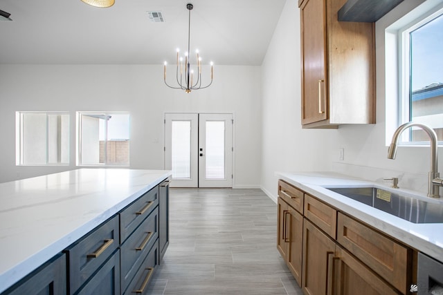 kitchen with light stone counters, a sink, a chandelier, french doors, and visible vents