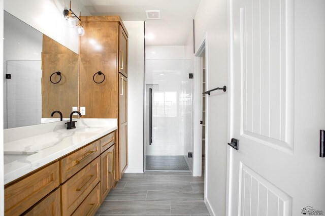 bathroom with visible vents, double vanity, baseboards, a sink, and a stall shower
