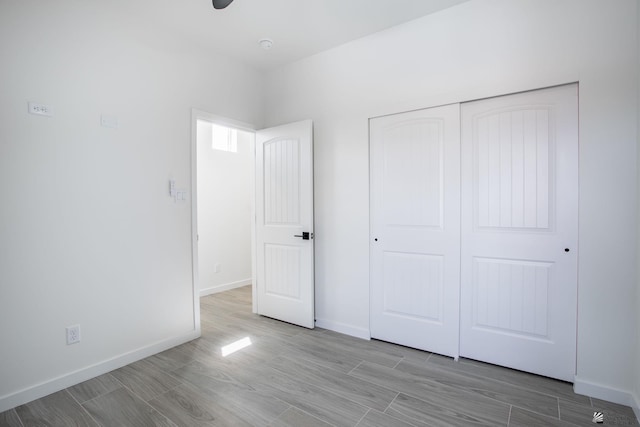 unfurnished bedroom with a closet, baseboards, and wood finished floors
