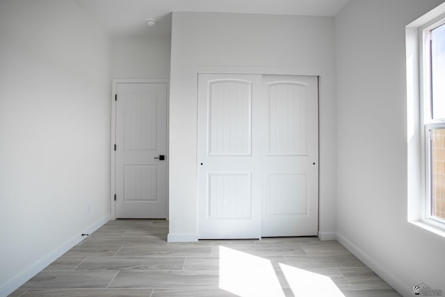 unfurnished bedroom with wood tiled floor, baseboards, and a closet