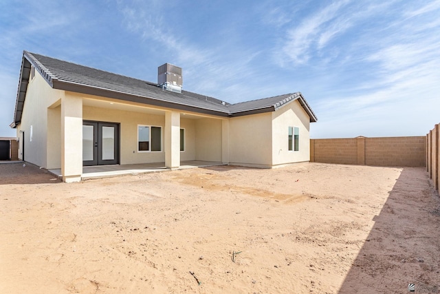 rear view of property featuring a fenced backyard, stucco siding, french doors, and a tile roof