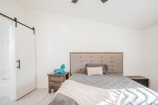 bedroom featuring light wood-type flooring, a barn door, and ceiling fan