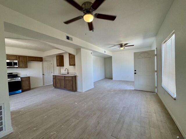 221 E Spring St, Somerton, AZ 85350 - unfurnished living room featuring a sink, a ceiling fan, light wood-style floors, and baseboards