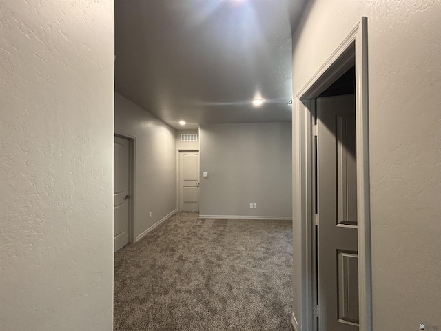 hallway with carpet flooring, baseboards, visible vents, and a textured wall