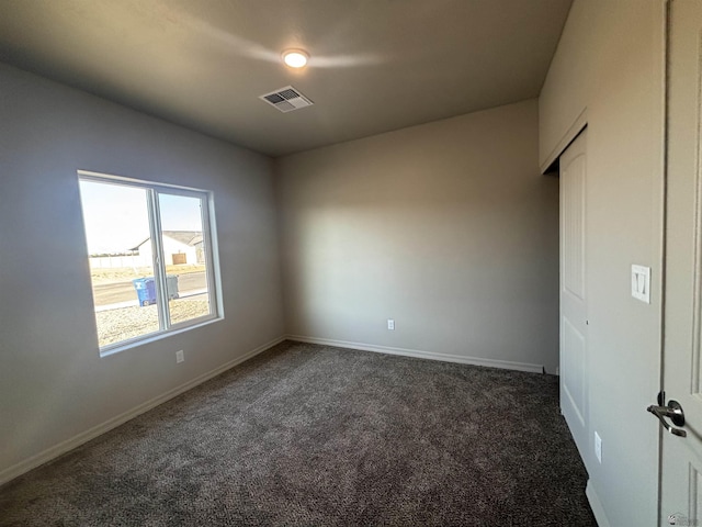 spare room with carpet floors, baseboards, and visible vents