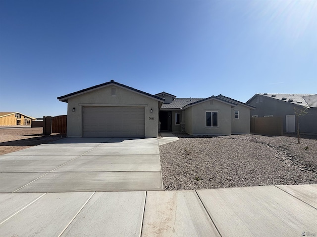 ranch-style home with a garage, fence, stucco siding, and driveway