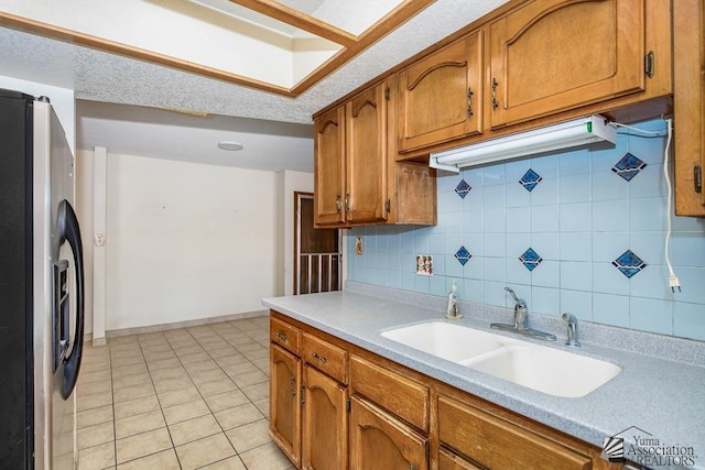 12344 E Calle Maria, Yuma, AZ 85367 - kitchen featuring brown cabinetry, a sink, light countertops, tasteful backsplash, and refrigerator with ice dispenser