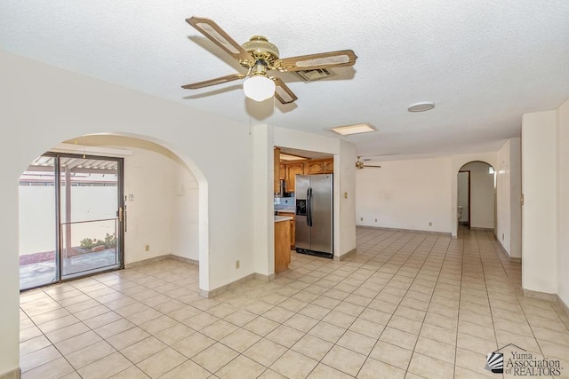 12344 E Calle Maria, Yuma, AZ 85367 - empty room with light tile patterned floors, arched walkways, ceiling fan, and a textured ceiling