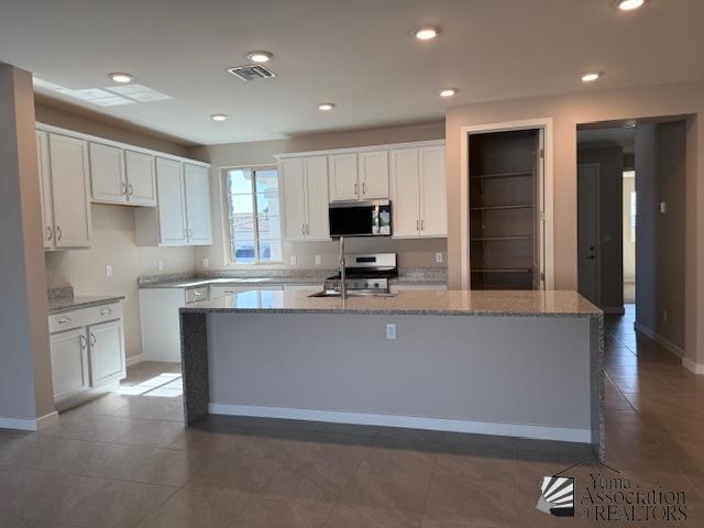 12373 S Drucilla Ln, Yuma, AZ 85367 - kitchen with stainless steel appliances, white cabinets, a center island with sink, light stone countertops, and recessed lighting