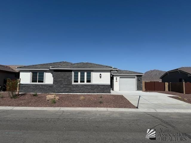 12373 S Drucilla Ln, Yuma, AZ 85367 - view of front of house featuring concrete driveway, an attached garage, stone siding, and stucco siding