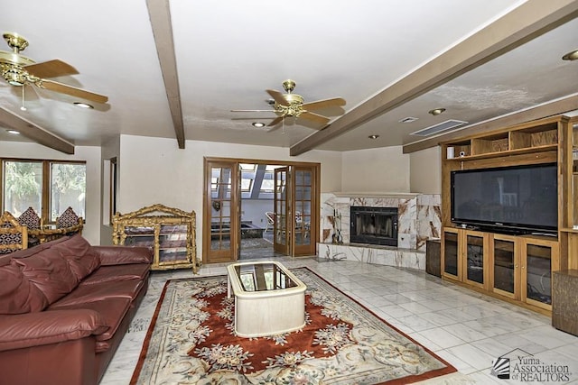 living room with beamed ceiling, french doors, ceiling fan, and a high end fireplace