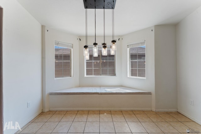 unfurnished dining area with light tile patterned floors, baseboards, and a wealth of natural light