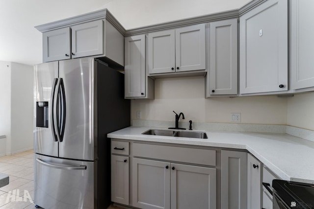 kitchen featuring stainless steel refrigerator with ice dispenser, a sink, and gray cabinets