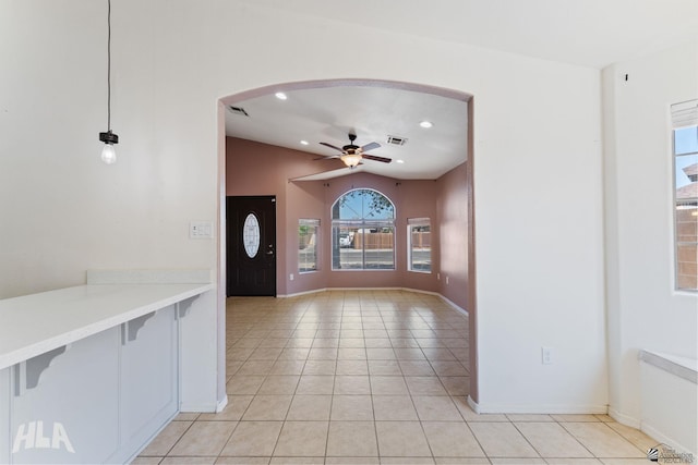 foyer with visible vents, ceiling fan, arched walkways, light tile patterned floors, and vaulted ceiling