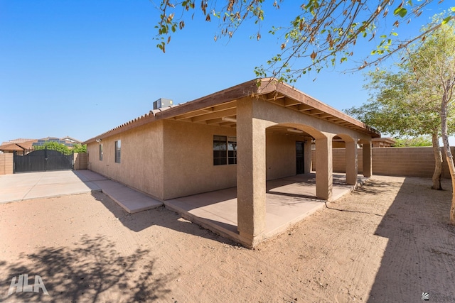 rear view of property with a patio, a gate, a fenced backyard, and stucco siding
