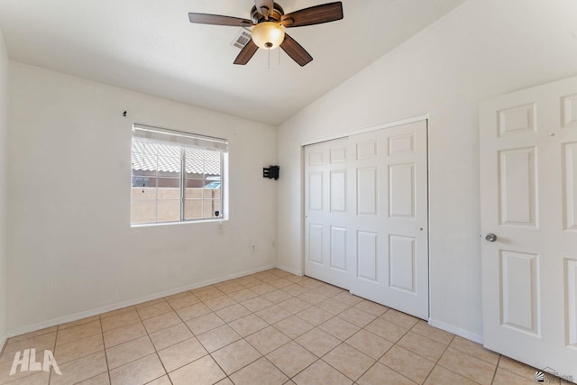 unfurnished bedroom featuring a closet, baseboards, lofted ceiling, and light tile patterned flooring