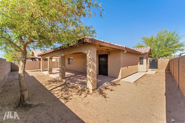 back of property featuring a fenced backyard, a tile roof, a patio area, and stucco siding