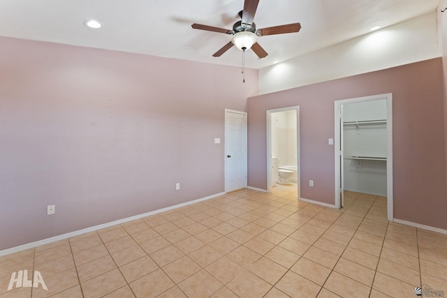 unfurnished bedroom featuring a walk in closet, light tile patterned floors, baseboards, a closet, and recessed lighting