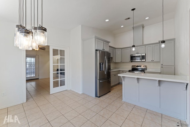 kitchen with light countertops, stainless steel appliances, a peninsula, light tile patterned floors, and visible vents