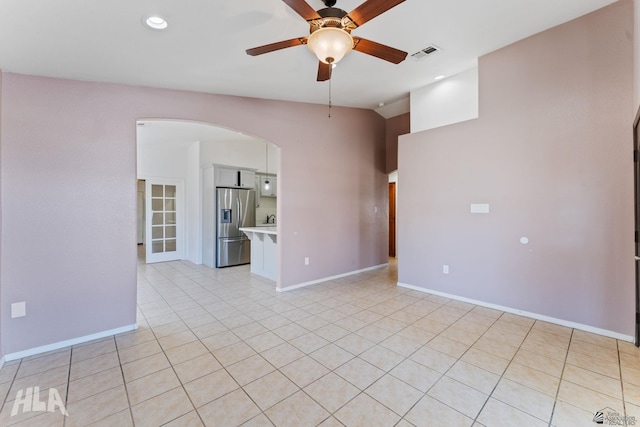 empty room with a ceiling fan, visible vents, arched walkways, baseboards, and light tile patterned flooring