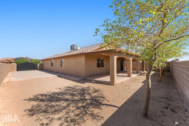 rear view of property with a patio, a tile roof, a fenced backyard, and stucco siding