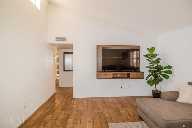 living area featuring high vaulted ceiling, baseboards, wood finished floors, and visible vents