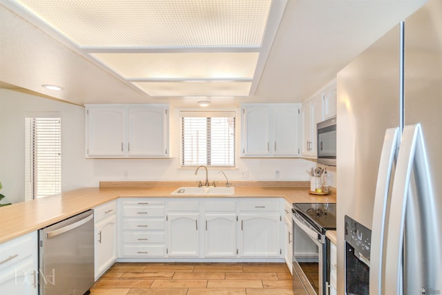 kitchen featuring a sink, appliances with stainless steel finishes, white cabinets, and light wood finished floors