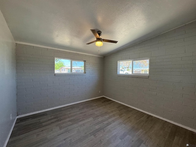 2641 S Las Palmas Vista Ave, Yuma, AZ 85364 - empty room with brick wall, baseboards, dark wood-type flooring, vaulted ceiling, and healthy amount of natural light