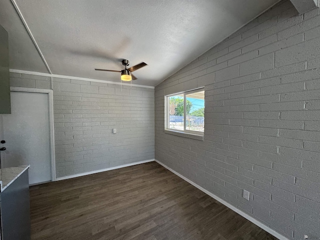 2641 S Las Palmas Vista Ave, Yuma, AZ 85364 - unfurnished room with baseboards, lofted ceiling, a ceiling fan, dark wood finished floors, and brick wall