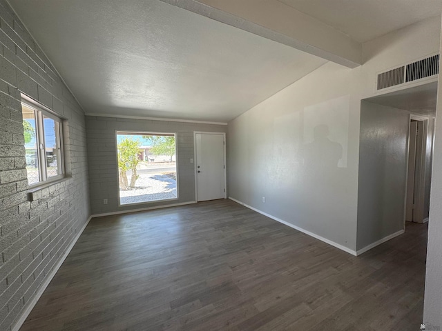 2641 S Las Palmas Vista Ave, Yuma, AZ 85364 - spare room featuring lofted ceiling, healthy amount of natural light, dark wood-type flooring, brick wall, and baseboards