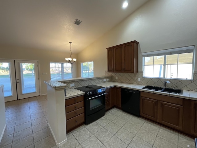 kitchen with a notable chandelier, a sink, tile counters, decorative backsplash, and black appliances