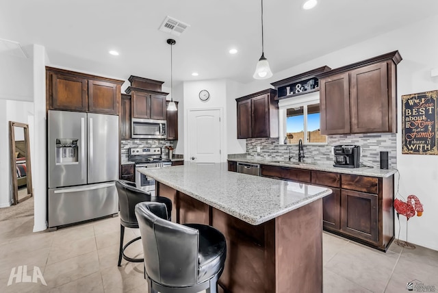 12590 E 48th Dr, Yuma, AZ 85367 - kitchen featuring appliances with stainless steel finishes, a sink, dark brown cabinetry, a center island, and backsplash