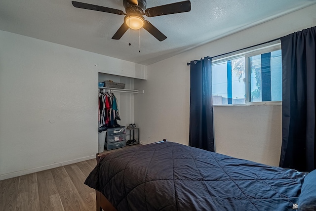 bedroom with baseboards, ceiling fan, a closet, and wood finished floors