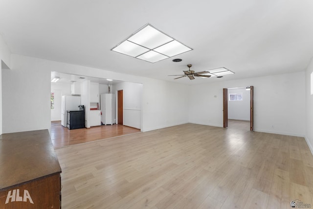 324 S 19th Ave, Yuma, AZ 85364 - unfurnished living room featuring plenty of natural light, baseboards, a ceiling fan, and light wood-style floors