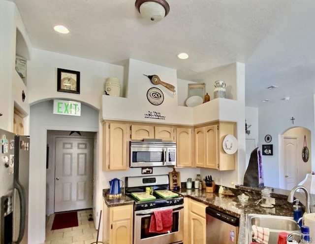 14393 E 53rd Ln, Yuma, AZ 85367 - kitchen with light brown cabinetry, dark countertops, arched walkways, a sink, and appliances with stainless steel finishes