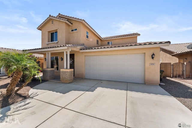mediterranean / spanish house featuring a tiled roof, driveway, a gate, and stucco siding