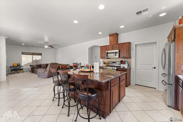 kitchen with visible vents, arched walkways, a breakfast bar, stainless steel appliances, and light tile patterned flooring