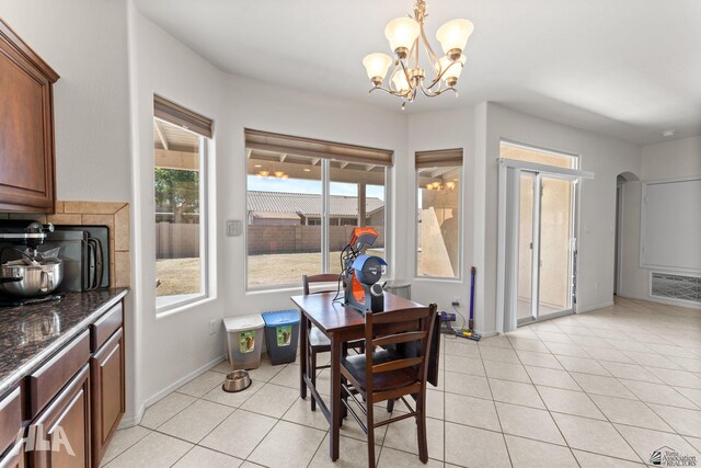 dining space featuring arched walkways, baseboards, an inviting chandelier, and light tile patterned floors