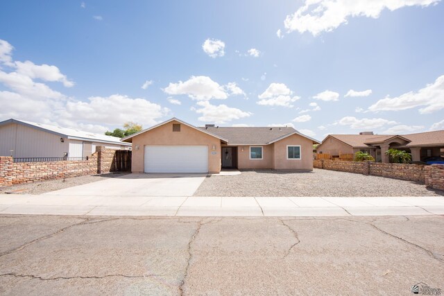 ranch-style house featuring an attached garage, stucco siding, fence, and concrete driveway