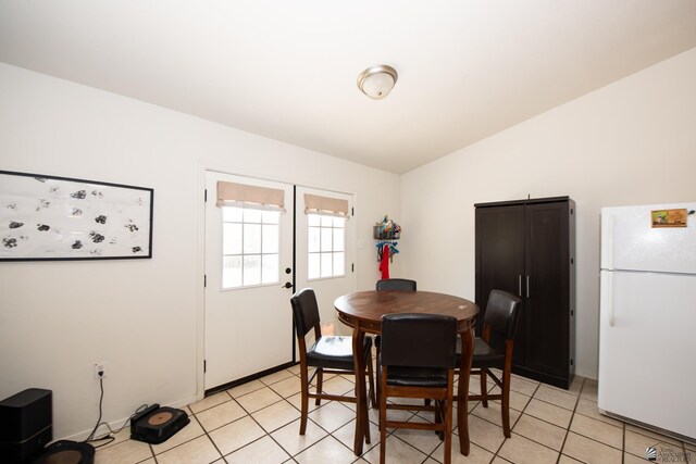 dining space with light tile patterned flooring and vaulted ceiling