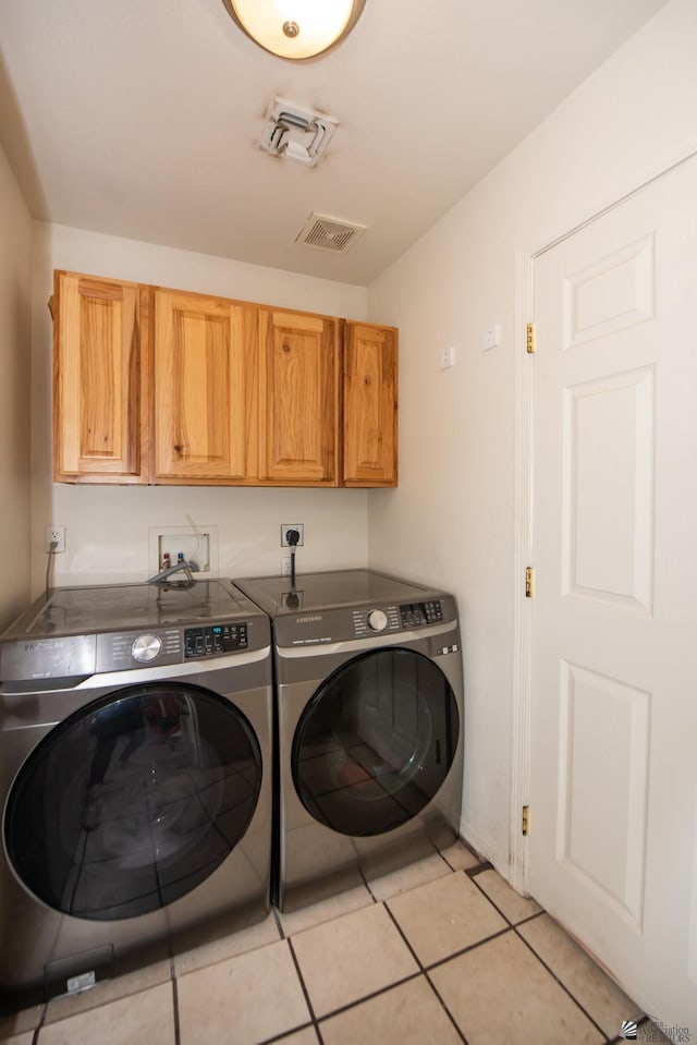 laundry area with light tile patterned floors, visible vents, cabinet space, and washer and dryer