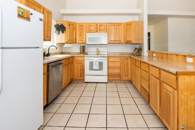 kitchen featuring white appliances, a peninsula, a sink, and light countertops
