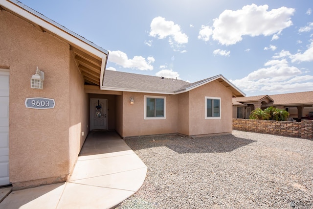 property entrance with roof with shingles and stucco siding