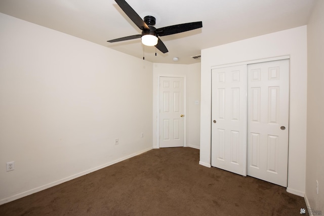 unfurnished bedroom featuring baseboards, a ceiling fan, a closet, and dark carpet