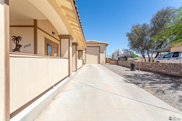 view of side of property featuring fence, a garage, driveway, and stucco siding