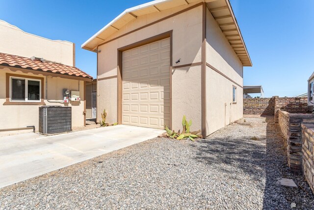 view of side of property with fence, stucco siding, concrete driveway, and a tile roof